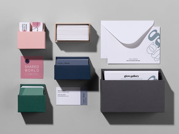 Flat lay picture of a pink, green, navy blue and beige business card boxes, white envelope with note card and grey note card box